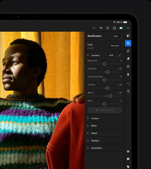 iPad Pro, face avant, orientation paysage, couleur noir sidéral, écran affichant la retouche d’une photo d’une personne portant un pull coloré, menu d’outils et d’effets ouvert sur la droite
