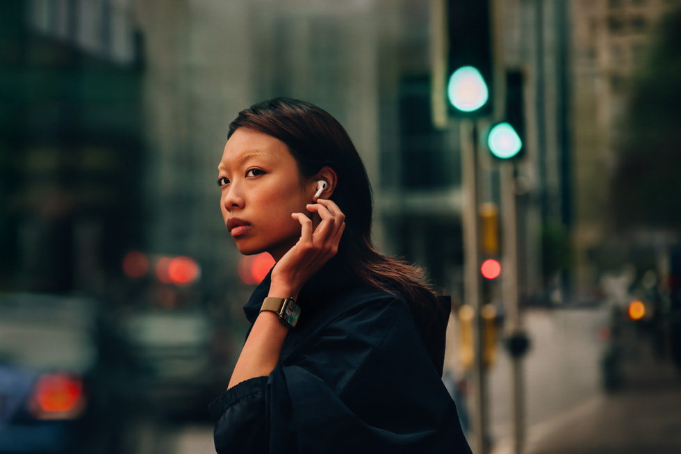 Une personne portant des AirPods 4 et une Apple Watch Series 10 se tient debout dans une rue en ville.