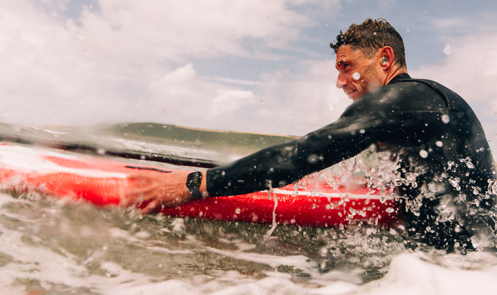 Une personne faisant du surf porte une Apple Watch Series 10 tout en se déplaçant sur une mer agitée.