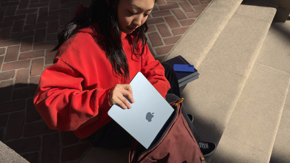 Une personne range un MacBook Air dans un sac à dos.