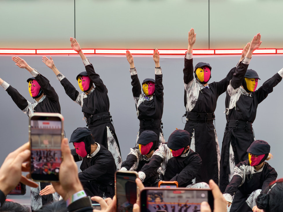 Dancers in orange-and-red masks perform at Apple Taikoo Li Chengdu in China.