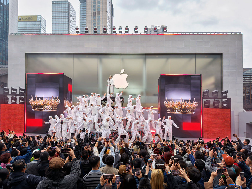 Dancers in white jumpsuits form a pyramid formation with Chris Lee singing at the top at Apple Taikoo Li Chengdu in China.