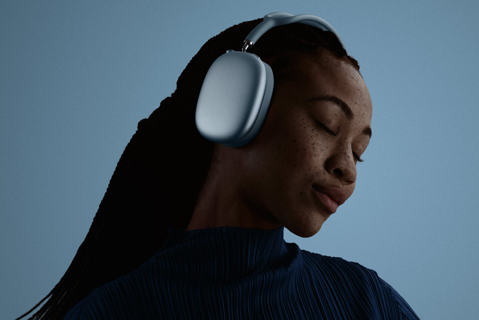 Foto seorang pengguna dengan mata tertutup sedang memakai AirPods Max 2 warna biru.