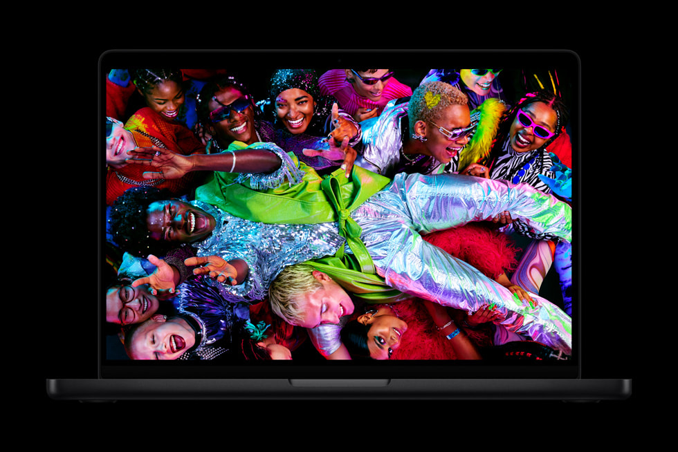 MacBook Pro shows a colourful screen with a crowd of people wearing vibrant clothes.