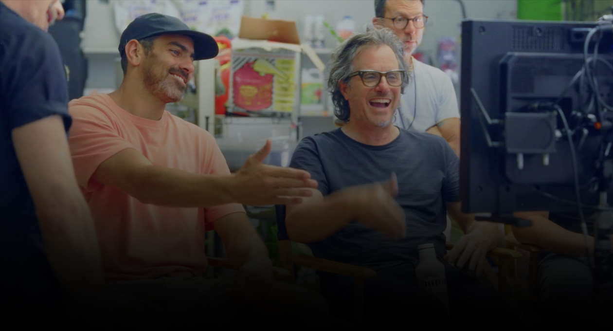 صورة لمخرجَين سينمائيَين جالسَين يشاهدان ويشيران إلى شاشة العرض.